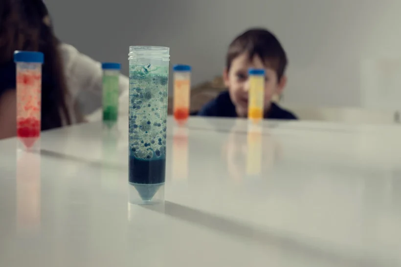 Lavalampe leicht erklärt Ein Junge beobachtet farbige Flüssigkeiten in Pipetten auf einem Tisch.